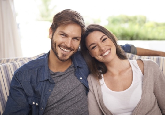 Smiling young man and woman sitting next to each other on couch