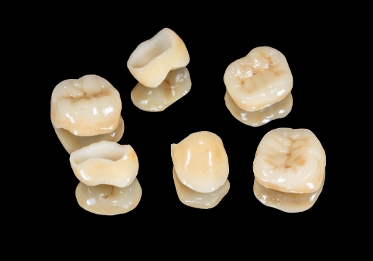 Six dental crowns against black background