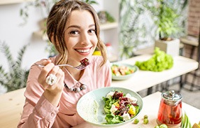 Woman smiling while eating healthy meal in kitchen