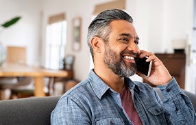 Man smiling while talking on phone at home