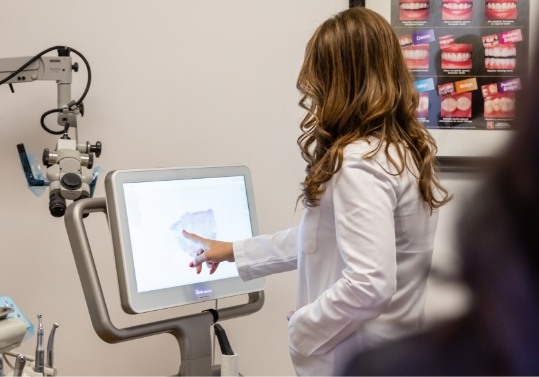 Doctor Saber pointing to computer screen showing digital scans of teeth