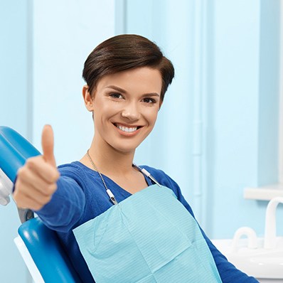 Female dental patient making thumbs-up gesture
