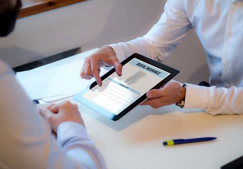Dentist and patient reviewing dental insurance on an electronic tablet 