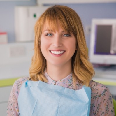 Smiling woman sitting in dental chair and wearing dental bib