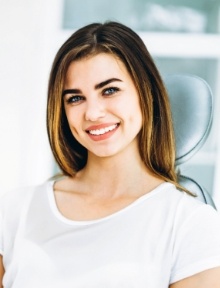 Woman in white tee shirt smiling in dental chair