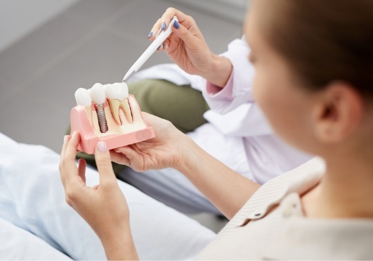 Dentist showing a patient a model of a dental implant