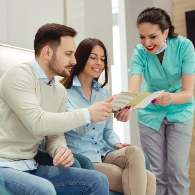 Dental team member talking to two patients about dental insurance in Fountain Valley