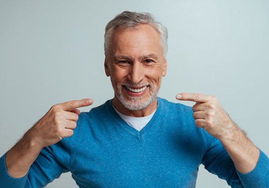 Happy senior man pointing at his dentures