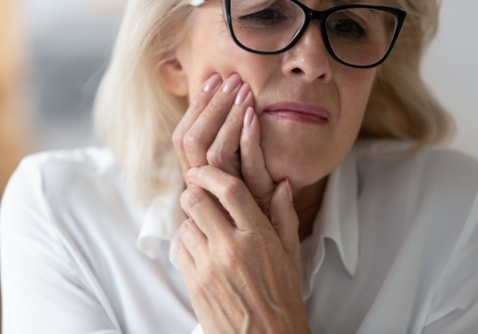 Older woman holding the side of her cheek in pain