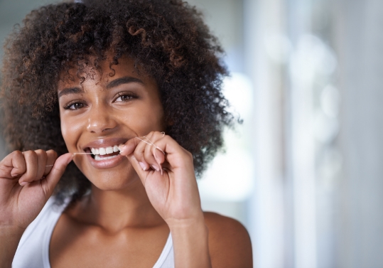 Woman smiling while flossing her teeth