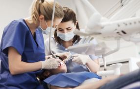 Dentist and assistant performing dental implant surgery