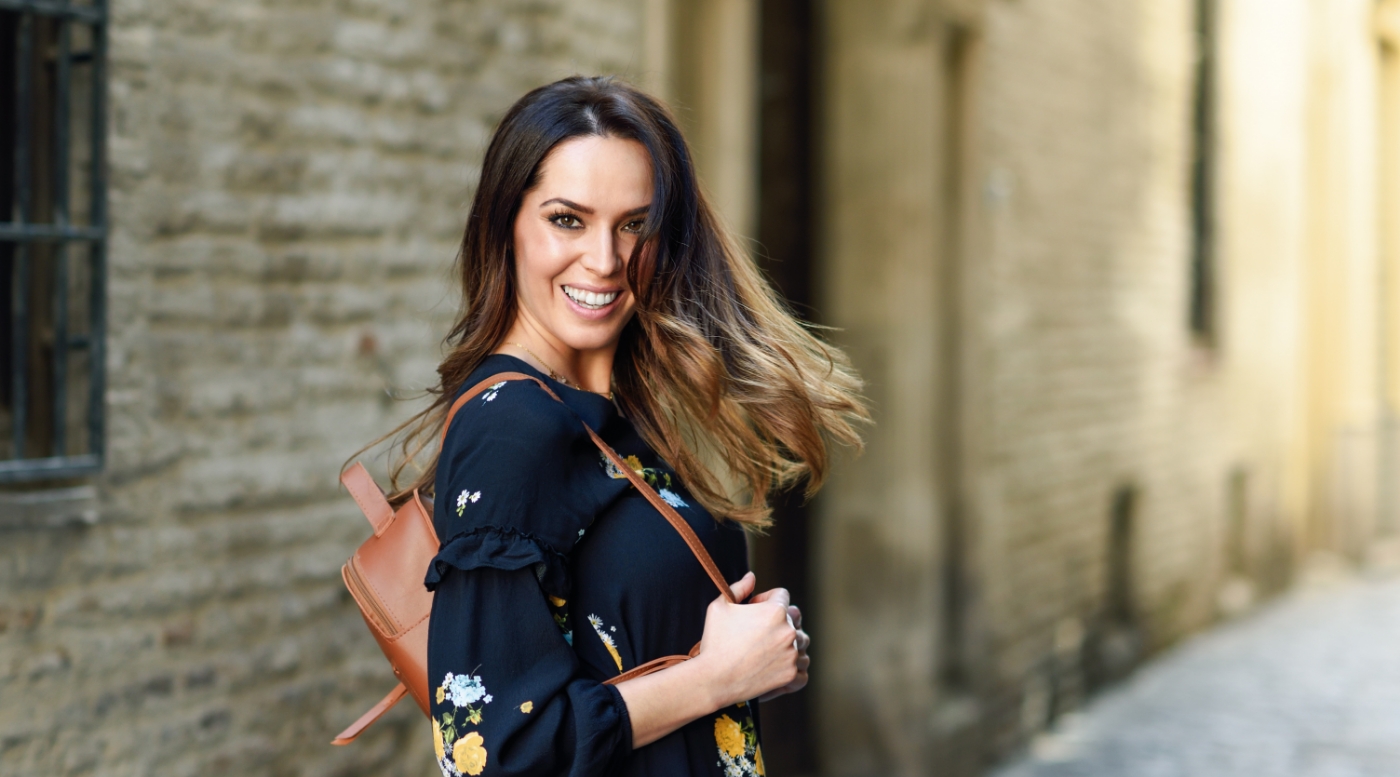 Smiling woman walking down sidewalk after visiting dentist in Fountain Valley