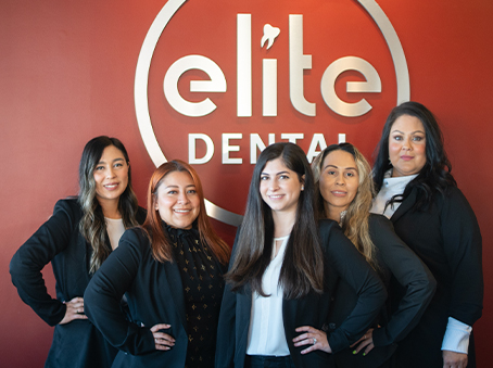 Dental team in front of Elite Dental of Fountain Valley sign inside of dental office