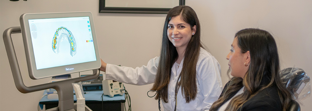 Doctor Saber showing a patient digital scans of their teeth on computer monitor