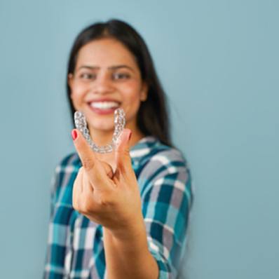 Happy woman holding aligner for Invisalign in Fountain Valley