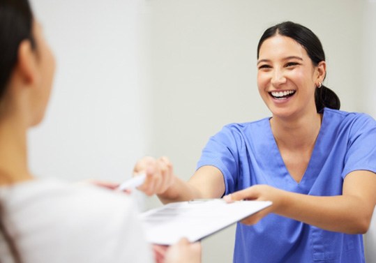 Dental team member handing clipboard to patient