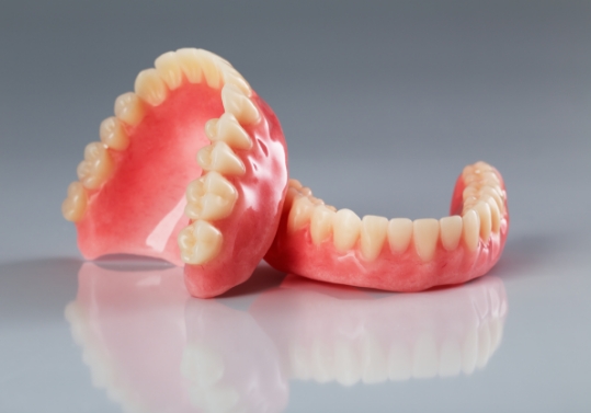 Two dentures resting on flat gray surface