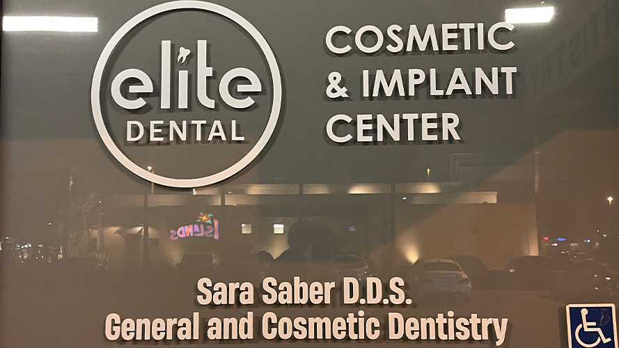 Sign on glass window reading Elite Dental Cosmetic and Implant Center Sara Saber D D S General and Cosmetic Dentistry