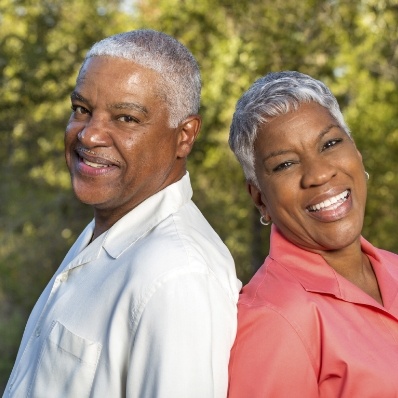 Senior man and woman smiling outdoors after dental services in Fountain Valley