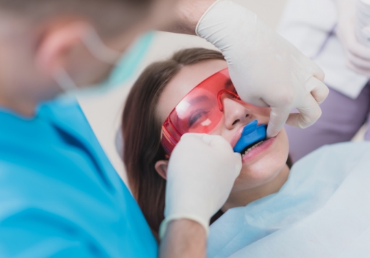 Young woman getting fluoride treatment during preventive dentistry visit