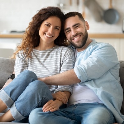 Man and woman smiling on couch after preventive dentistry in Fountain Valley