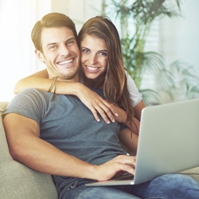 Smiling man and woman on laptop requesting a dental appointment in Fountain Valley