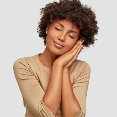 Smiling woman making pillow shape with her hands and pretending to sleep