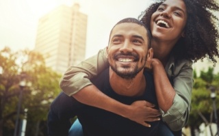 Man giving woman piggyback ride with skyscraper in background