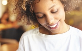 Woman in white shirt smiling and looking at the ground