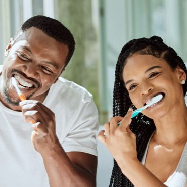 Couple in front of bathroom mirror, brushing their teeth