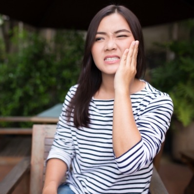 Woman holding her cheek in pain needing wisdom tooth extractions in Fountain Valley