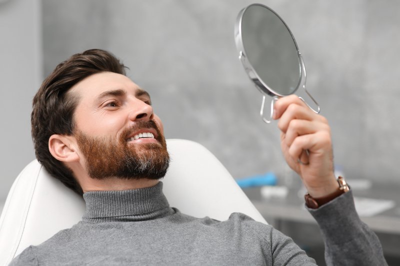 man looking at his smile in the mirror 
