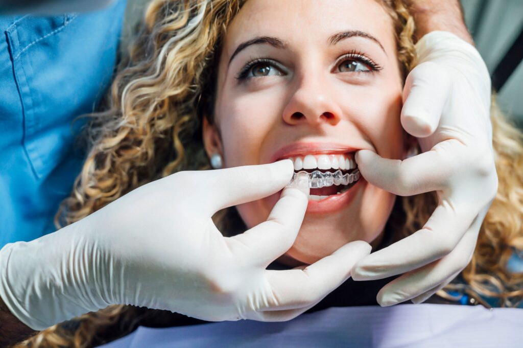 Dentist putting Invisalign over woman's upper arch