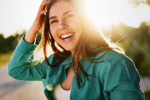 Woman with dental implants smiling in the sun
