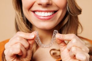 Woman smiling while holding her Invisalign tray