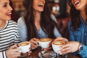 Women laughing and having coffee together.